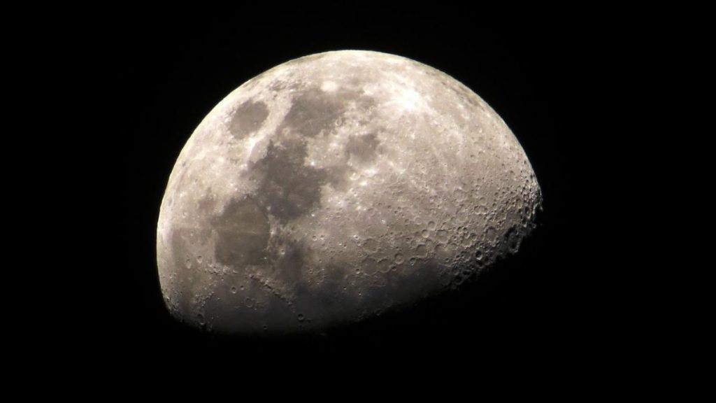 A part of the moon showing craters against the black night sky.