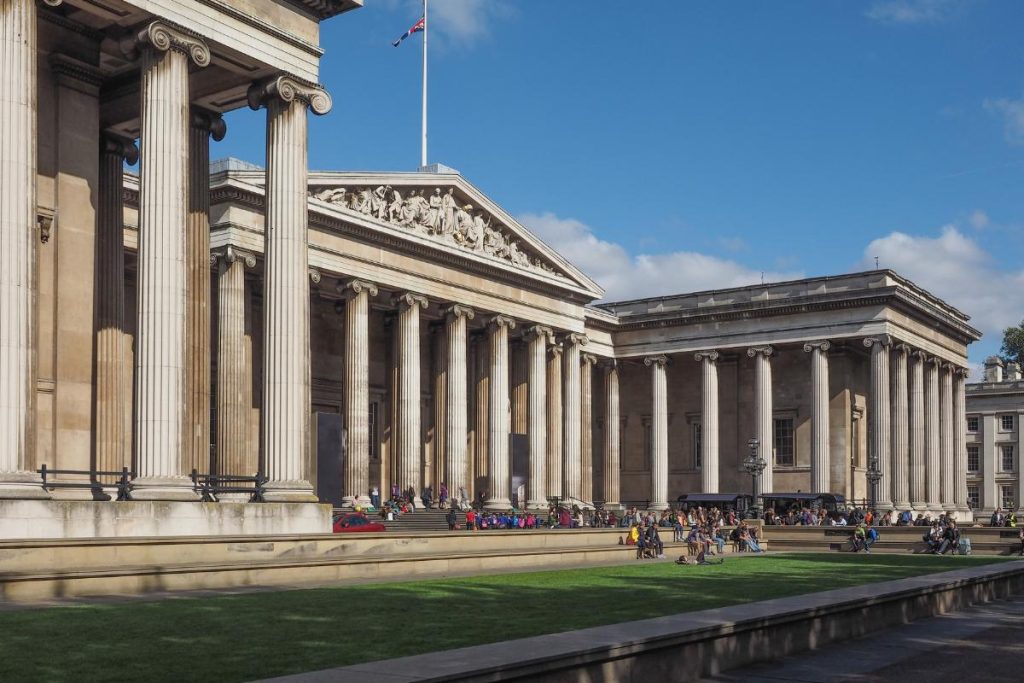 The outside of the front of The British Museum in the sunshine.